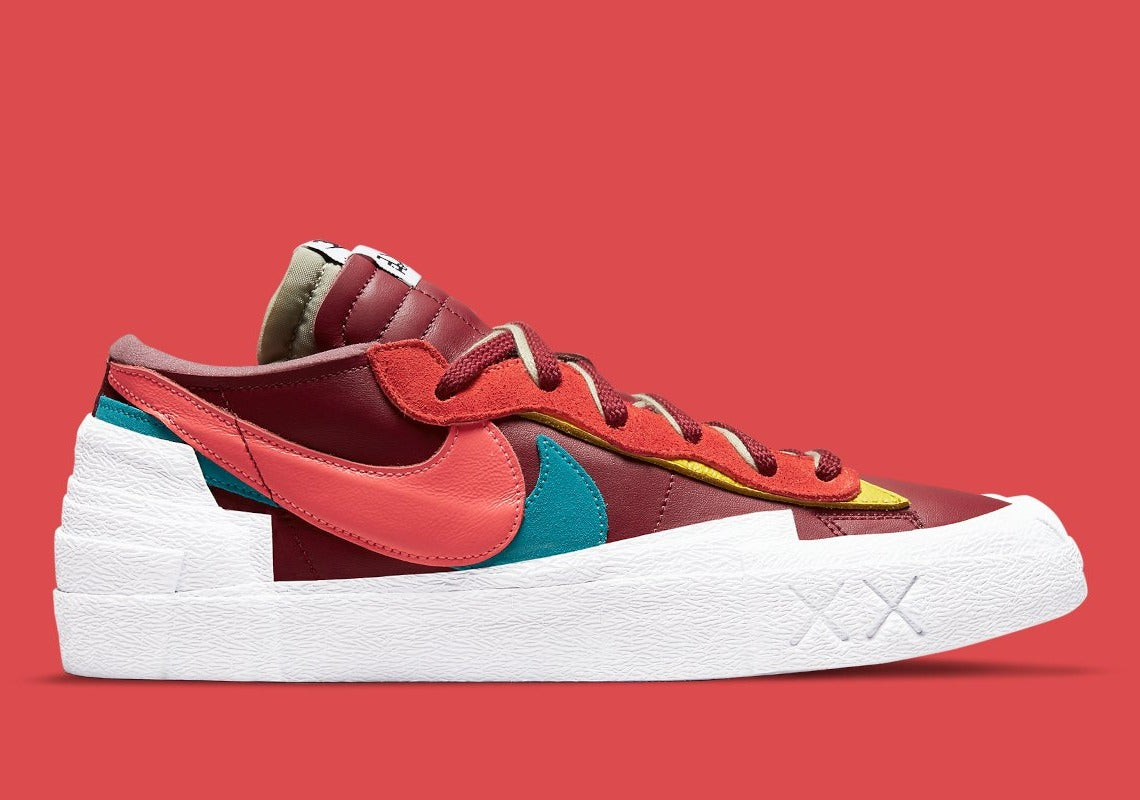 Nike Blazer Low sacai KAWS Red – sneaker rouge en cuir avec double Swoosh multicolore et logo XX de KAWS, vue de face