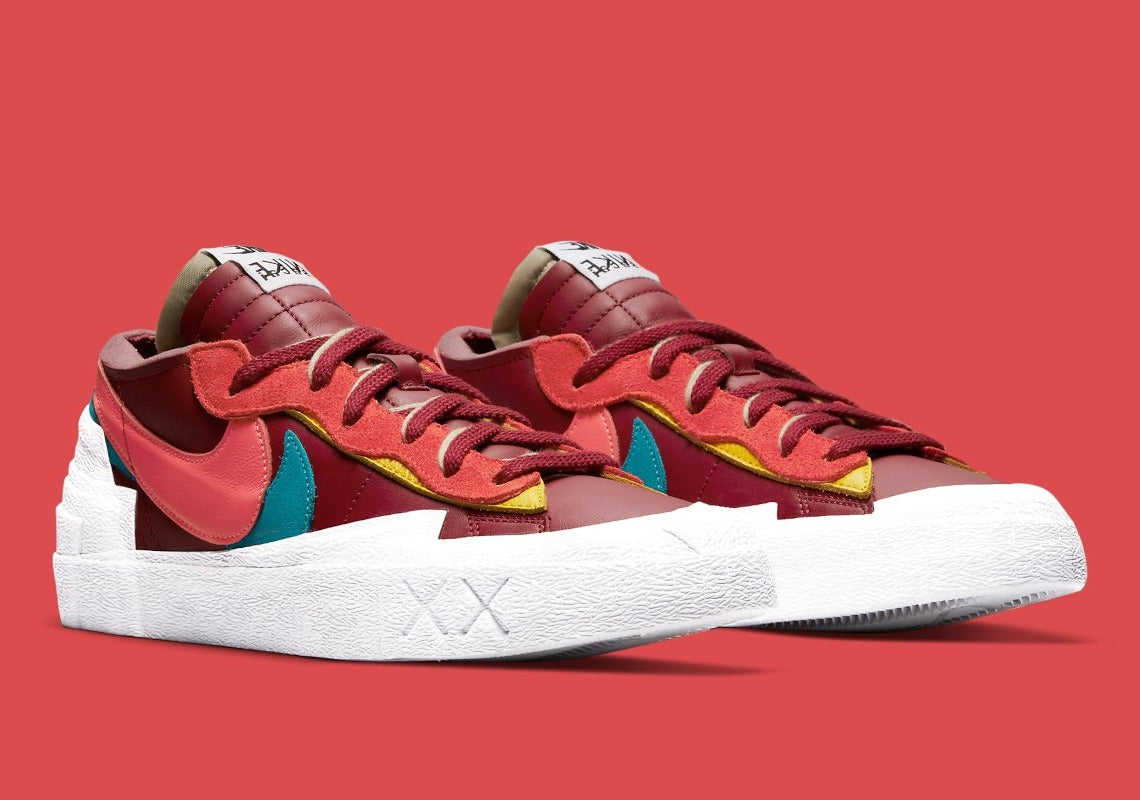 Nike Blazer Low sacai KAWS Red – sneaker rouge en cuir avec double Swoosh multicolore et logo XX de KAWS, vue de profil