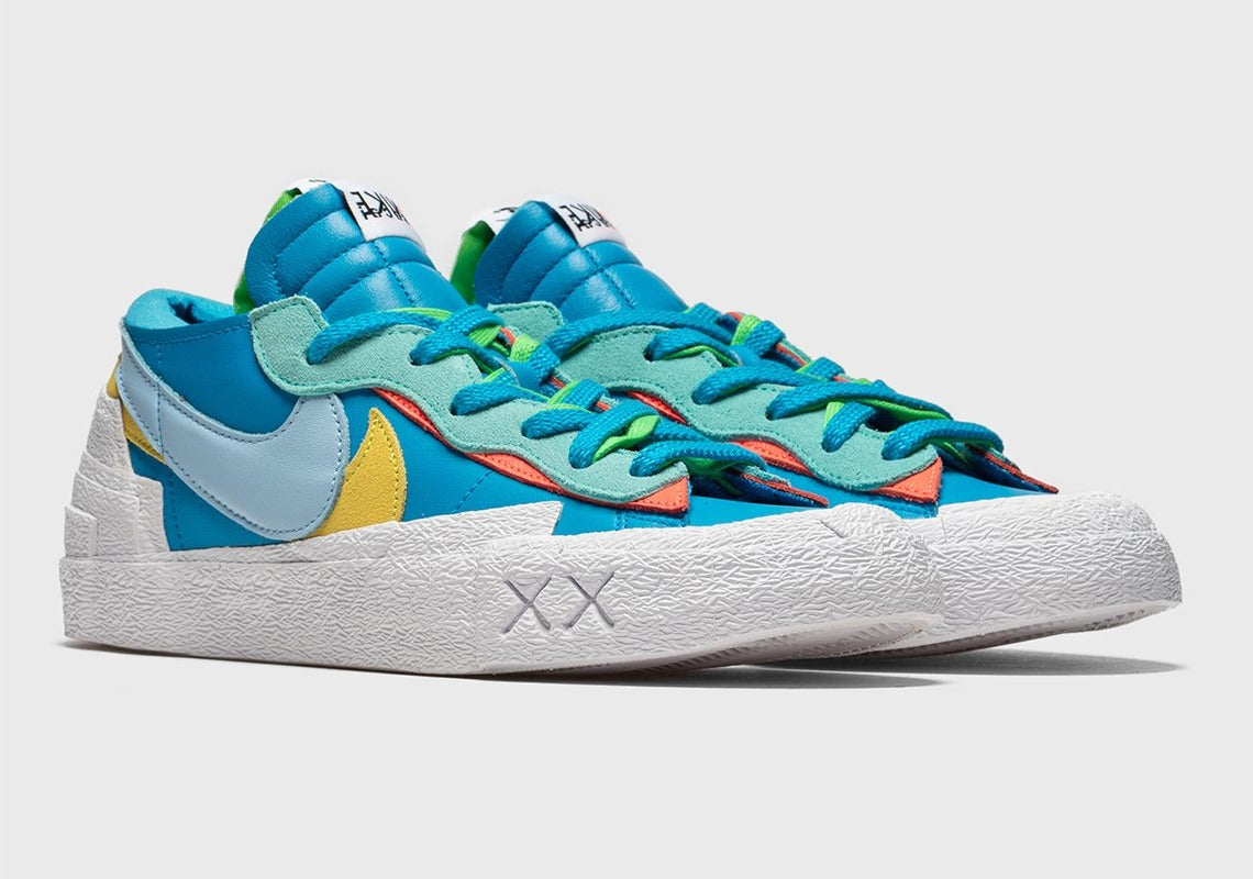 Nike Blazer Low sacai KAWS Neptune Blue – sneaker bleue en cuir avec double Swoosh multicolore et logo XX de KAWS, vue de profil