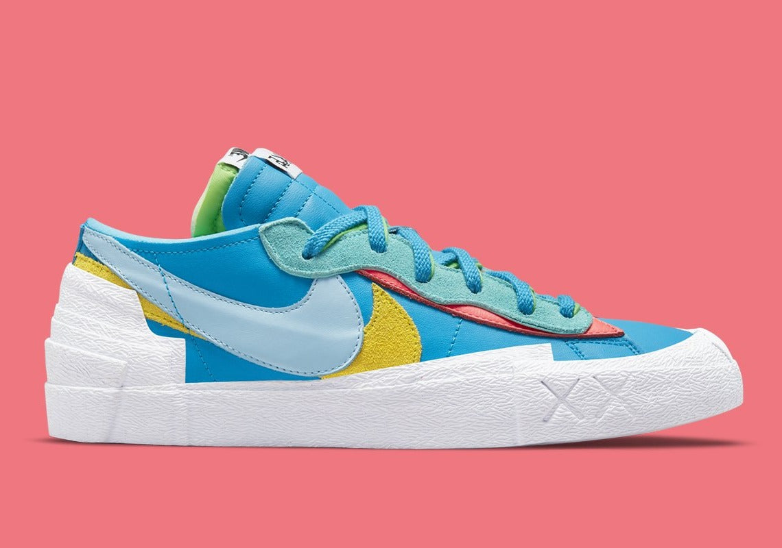 Nike Blazer Low sacai KAWS Neptune Blue – sneaker bleue en cuir avec double Swoosh multicolore et logo XX de KAWS, vue de face