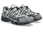 Image de la ASICS GEL-CUMULUS 16 TG Grey Black/Pure Silver, sneaker gris foncé et noir avec accents argent métallisé, tige en mesh et surpiqûres techniques, semelle avec amorti GEL™ visible. Vue de 3/4 face. 