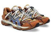 Image de la ASICS GEL-CUMULUS 16 × TOGA “Brown Blue Pure Silver”, sneaker marron terre et bleu vif avec détails argentés métallisés, tige mesh et superpositions synthétiques, amorti GEL visible, collaboration ASICS × TOGA. Vue de 3/4 face. 