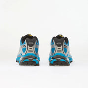 Salomon XT-4 OG Silver Black Transcend Blue avec tige en maille respirante argentée, renforts noirs, détails Transcend Blue, système Quicklace™ et semelle Contagrip® à crampons.