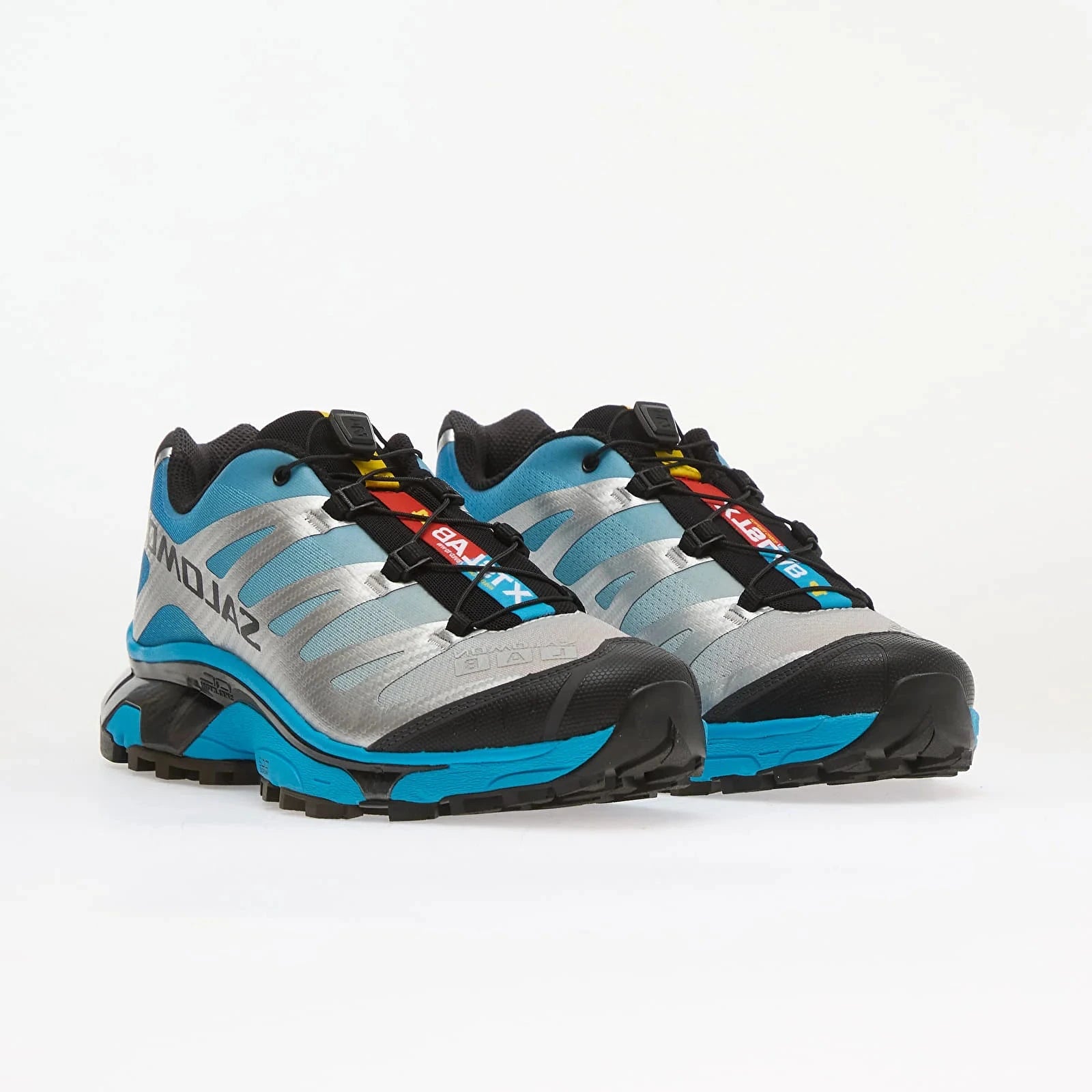 Salomon XT-4 OG Silver Black Transcend Blue avec tige en maille respirante argentée, renforts noirs, détails Transcend Blue, système Quicklace™ et semelle Contagrip® à crampons.