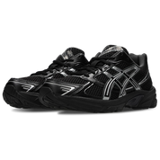 Image de l’ASICS GEL-1130 Black/Pure Silver – sneaker noire en mesh et cuir synthétique avec détails argentés métallisés, insert GEL® visible au talon. (vue de 3/4)