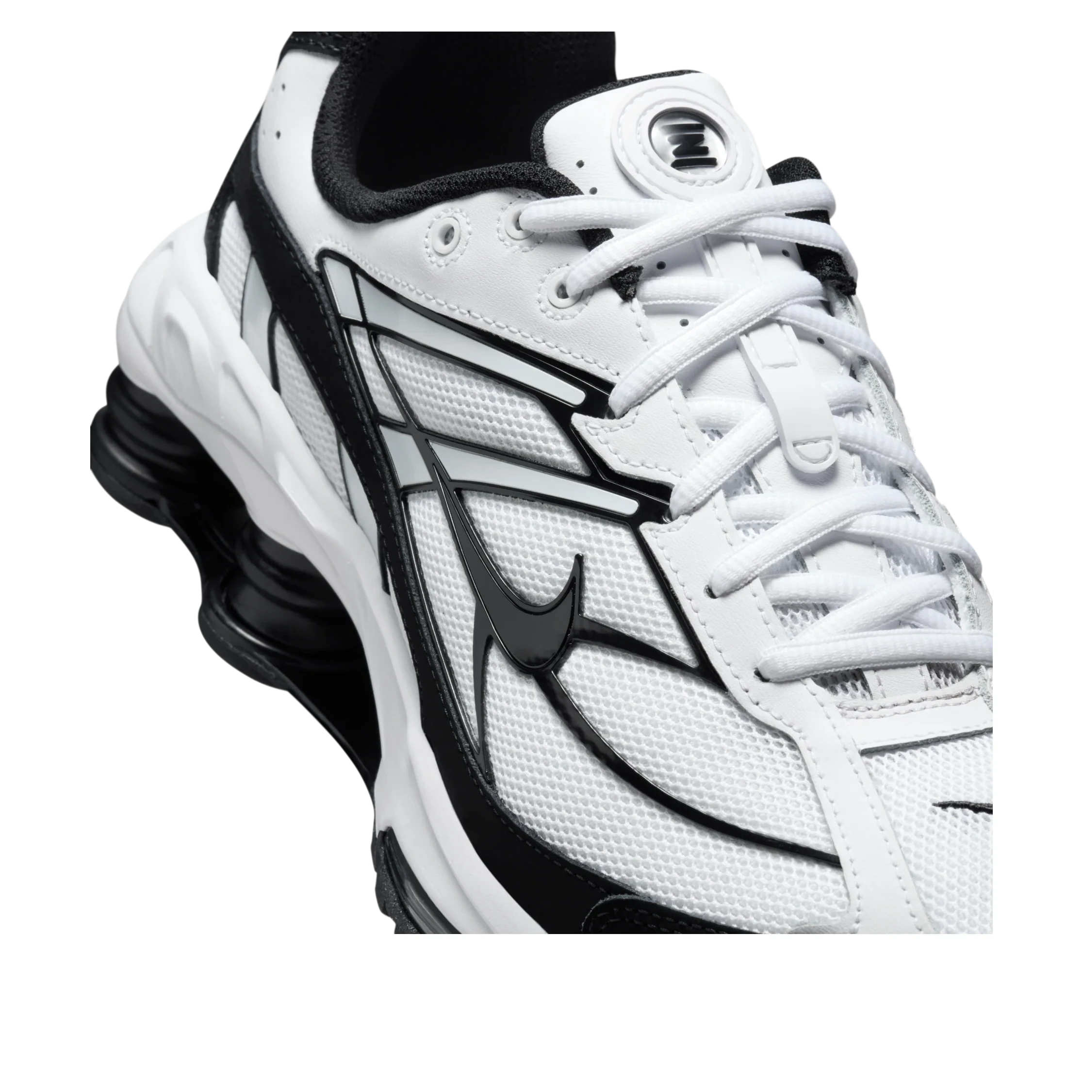 Vue zoomée sur les détails latéraux de la Nike Shox Ride 2 White Black avec tige en mesh respirant blanc, empiècements synthétiques noirs, amorti Nike Shox au talon et semelle extérieure en caoutchouc.