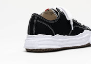 Découvrez la Maison Mihara Yasuhiro Hank OG Sole Canvas Low Black, une sneaker en toile noire avec semelle OG Sole sculptée en caoutchouc et silhouette basse au design expérimental.