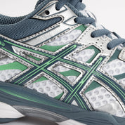 Sneaker ASICS Gel-Cumulus 16 White Ironclad en mesh blanc avec détails gris métallisés, amorti GEL et silhouette rétro-running technique.