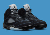 Air Jordan 5 Retro Black University Blue 2026 en nubuck noir avec accents bleus, languette réfléchissante et unité Air visible au talon.