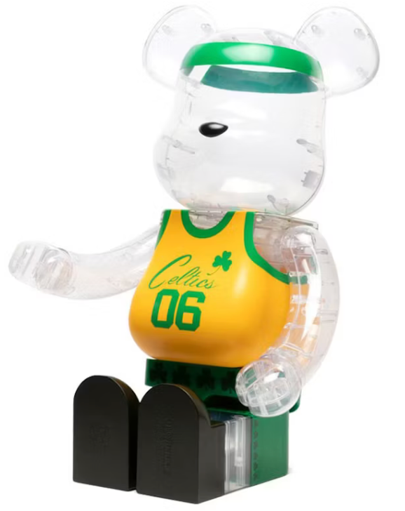 Image du Bearbrick x Bodega x NBA Worldwide Respect Boston Celtics 1000%, figurine géante transparente avec motifs verts et jaunes inspirés de la franchise NBA et éléments graphiques Bodega. Vu de face assis. 