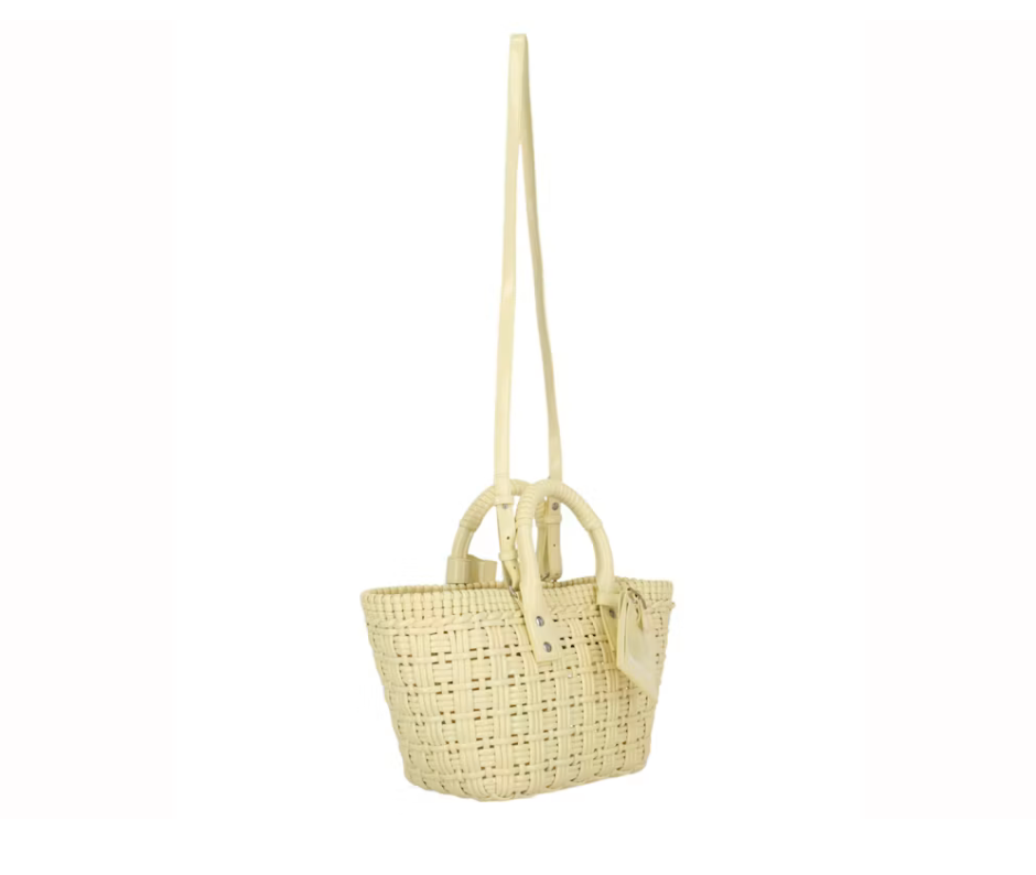 Balenciaga Bistro Strap Basket XS Yellow en matière tressée jaune avec deux anses roulées, étiquette Balenciaga et bandoulière amovible.