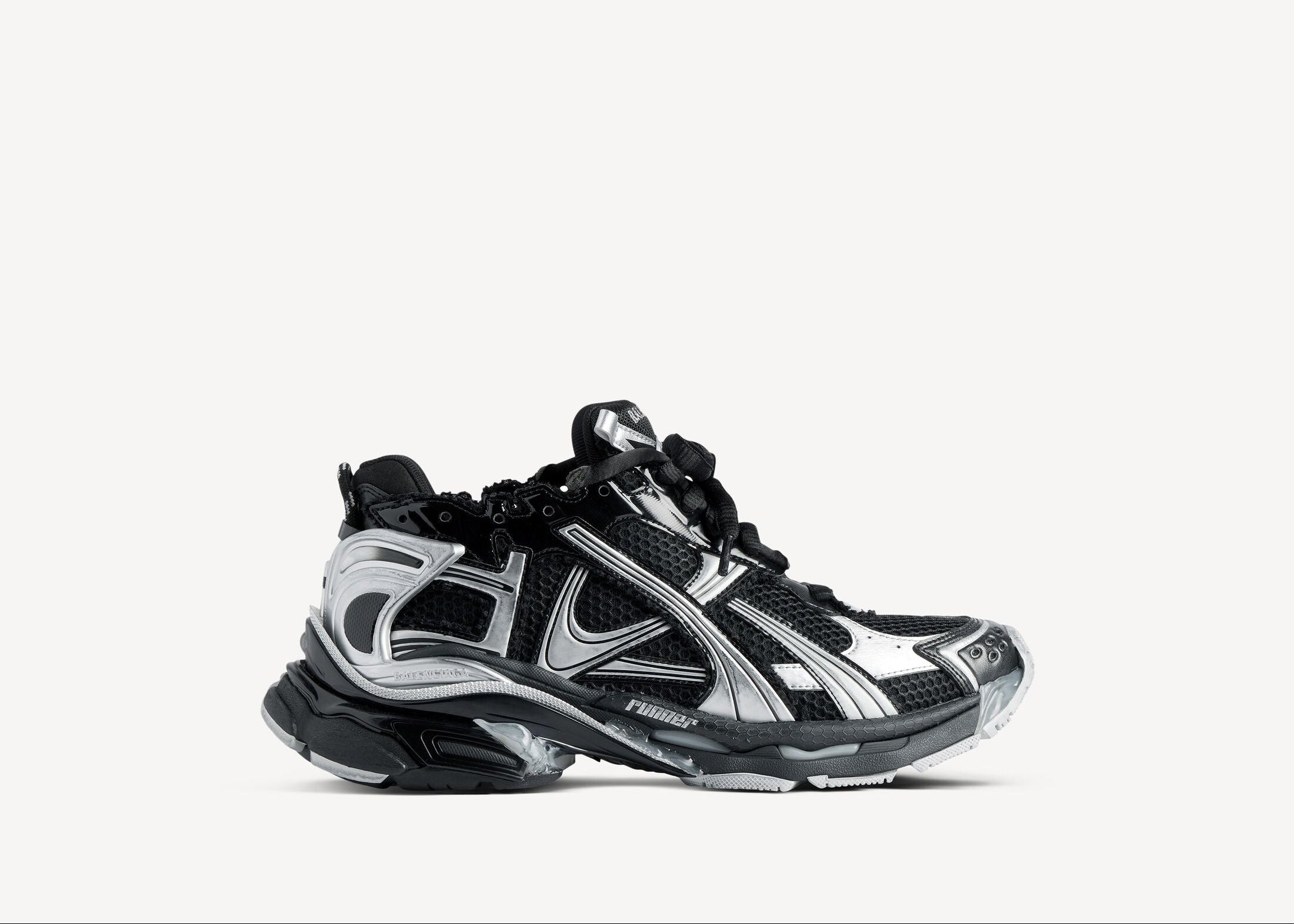 Balenciaga Runner Black Silver avec tige en mesh respirant, empiècements en cuir et matières synthétiques noirs et argentés, silhouette running déstructurée et semelle épaisse en caoutchouc.