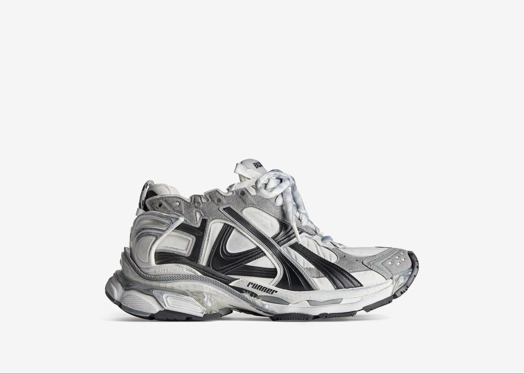 Balenciaga Runner Grey White Black avec tige en mesh respirant, empiècements en cuir gris, blanc et noir, semelle intermédiaire en mousse et silhouette inspirée du running rétro.