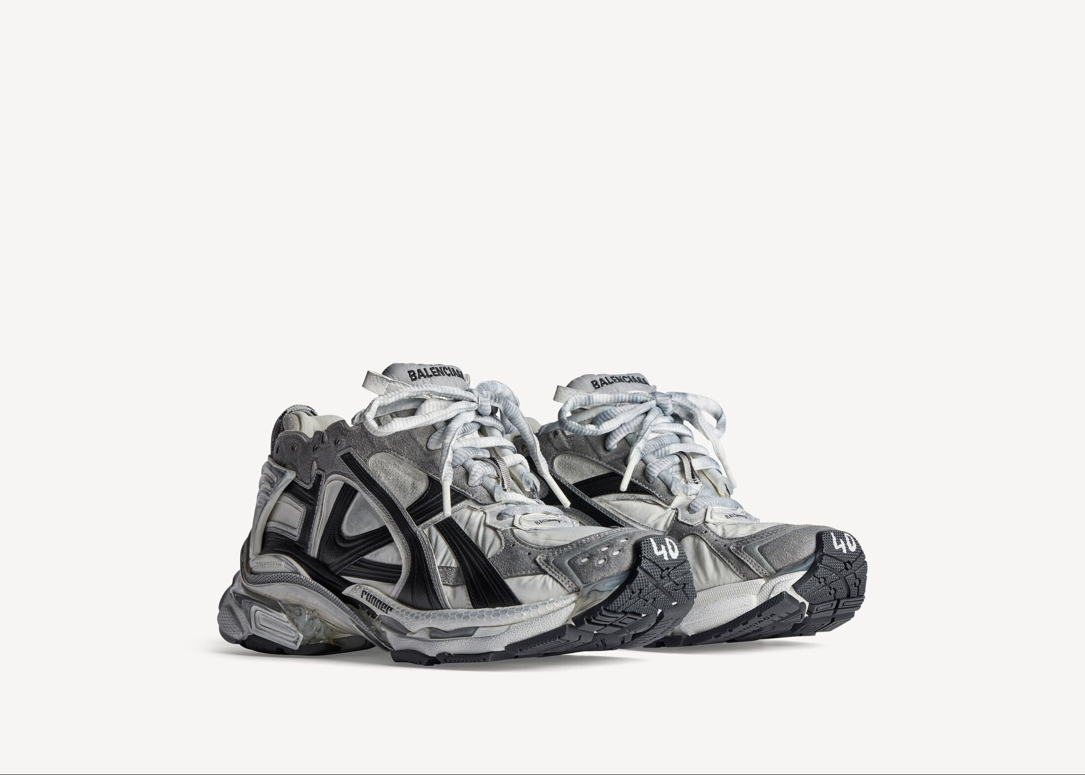 Balenciaga Runner Grey White Black avec tige en mesh respirant, empiècements en cuir gris, blanc et noir, semelle intermédiaire en mousse et silhouette inspirée du running rétro.