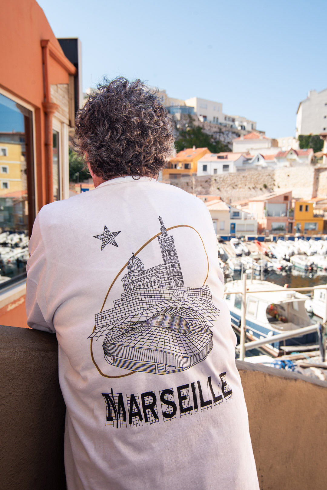 T-shirt blanc Global Sneakers x Ailleurs/Higher Marseille – sérigraphie artisanale avec Notre-Dame de la Garde et le Vélodrome", vue de dos porté
