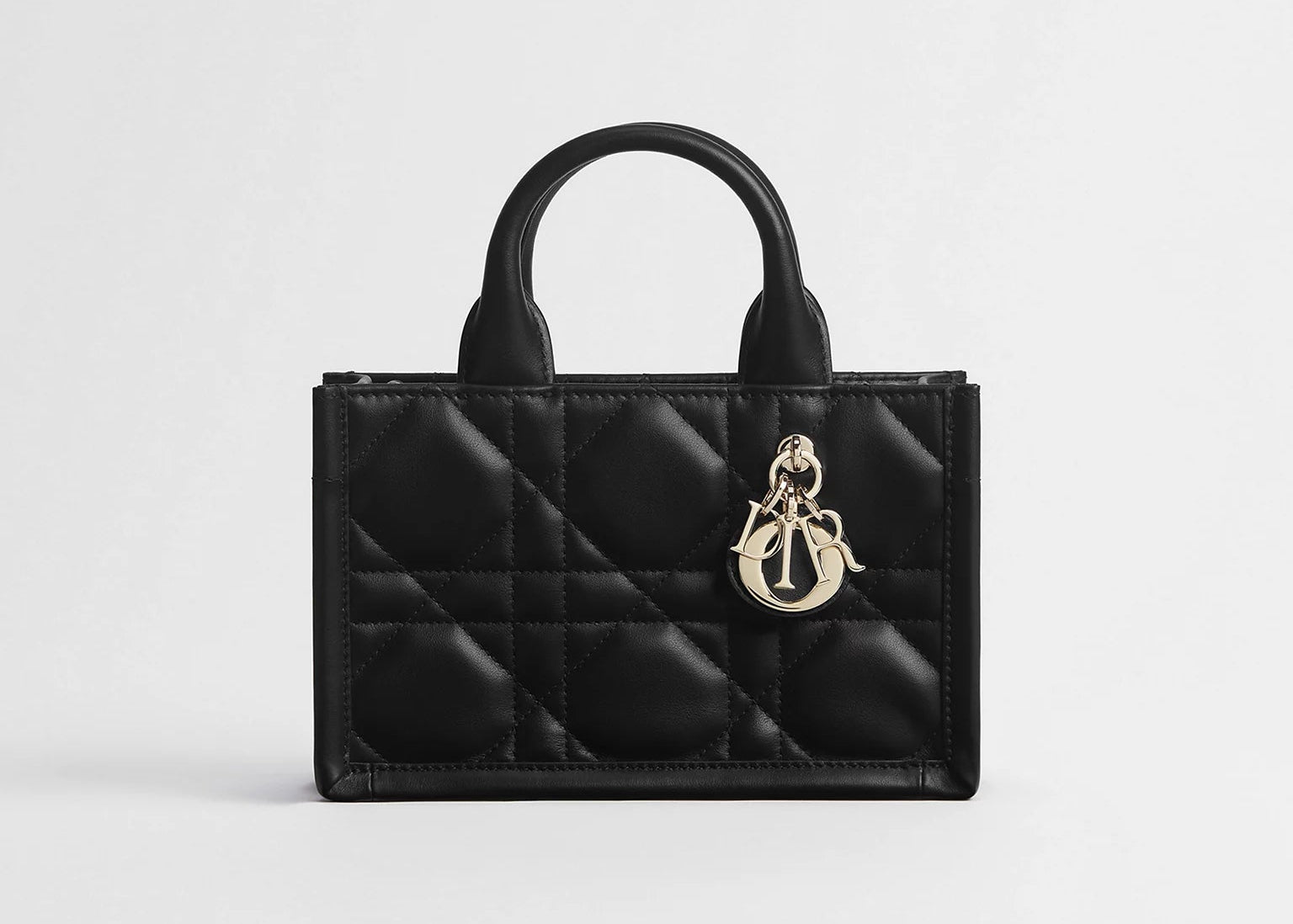 Dior Mini Dior Book Macrocannage Calfskin Tote Black, mini sac cabas en cuir de veau noir avec surpiqûres Macrocannage, deux anses et charms D.I.O.R. dorés vu de face. 