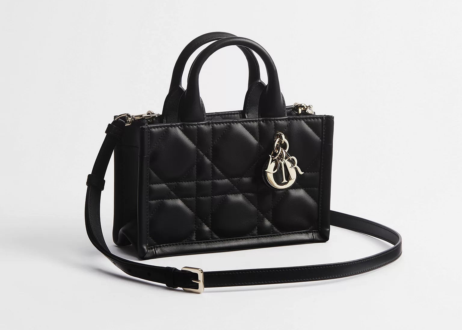 Dior Mini Dior Book Macrocannage Calfskin Tote Black, mini sac cabas en cuir de veau noir avec surpiqûres Macrocannage, deux anses et charms D.I.O.R. dorés vu de 3/4 face. 