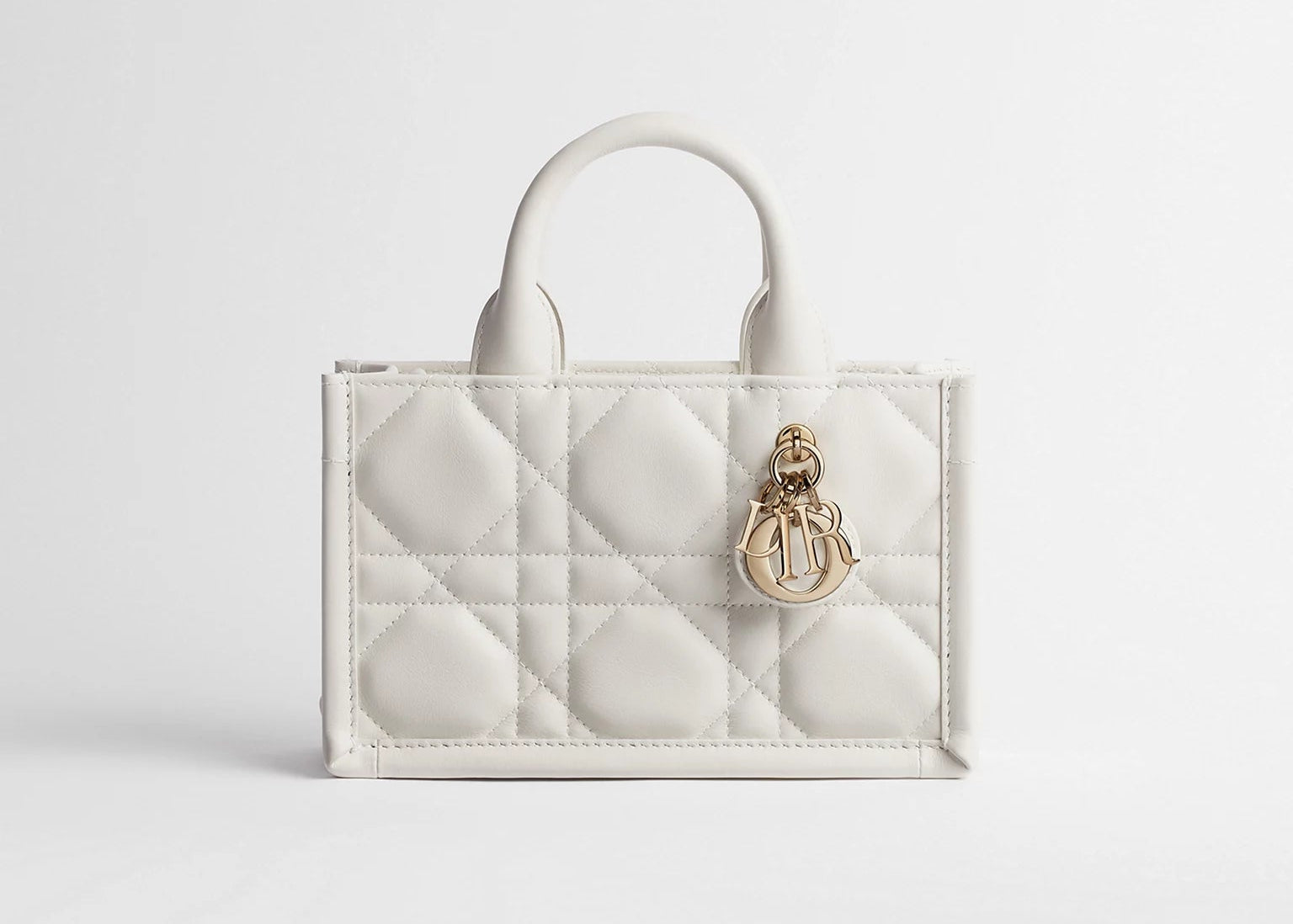 Dior Mini Dior Book Macrocannage Calfskin Tote Latte, mini sac cabas en cuir de veau blanc crème, surpiqûres Macrocannage et charms D.I.O.R. dorés vu de face. 