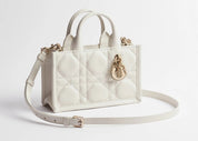 Dior Mini Dior Book Macrocannage Calfskin Tote Latte, mini sac cabas en cuir de veau blanc crème, surpiqûres Macrocannage et charms D.I.O.R. dorés vu de 3/4 face. 
