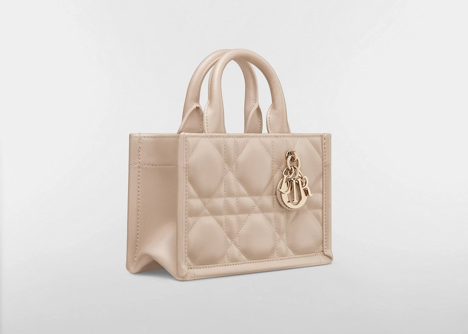 Dior Mini Dior Book Macrocannage Calfskin Tote Powder Beige, mini sac cabas en cuir de veau beige poudré avec surpiqûres Cannage et charms D.I.O.R. dorés vue de 3/4 face. 