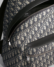 Vue zoomée sur les détails du Dior Rider Backpack Oblique Blue/Black, sac à dos en toile jacquard à motif Dior Oblique, finitions en cuir sombre, poche avant zippée et bretelles réglables.