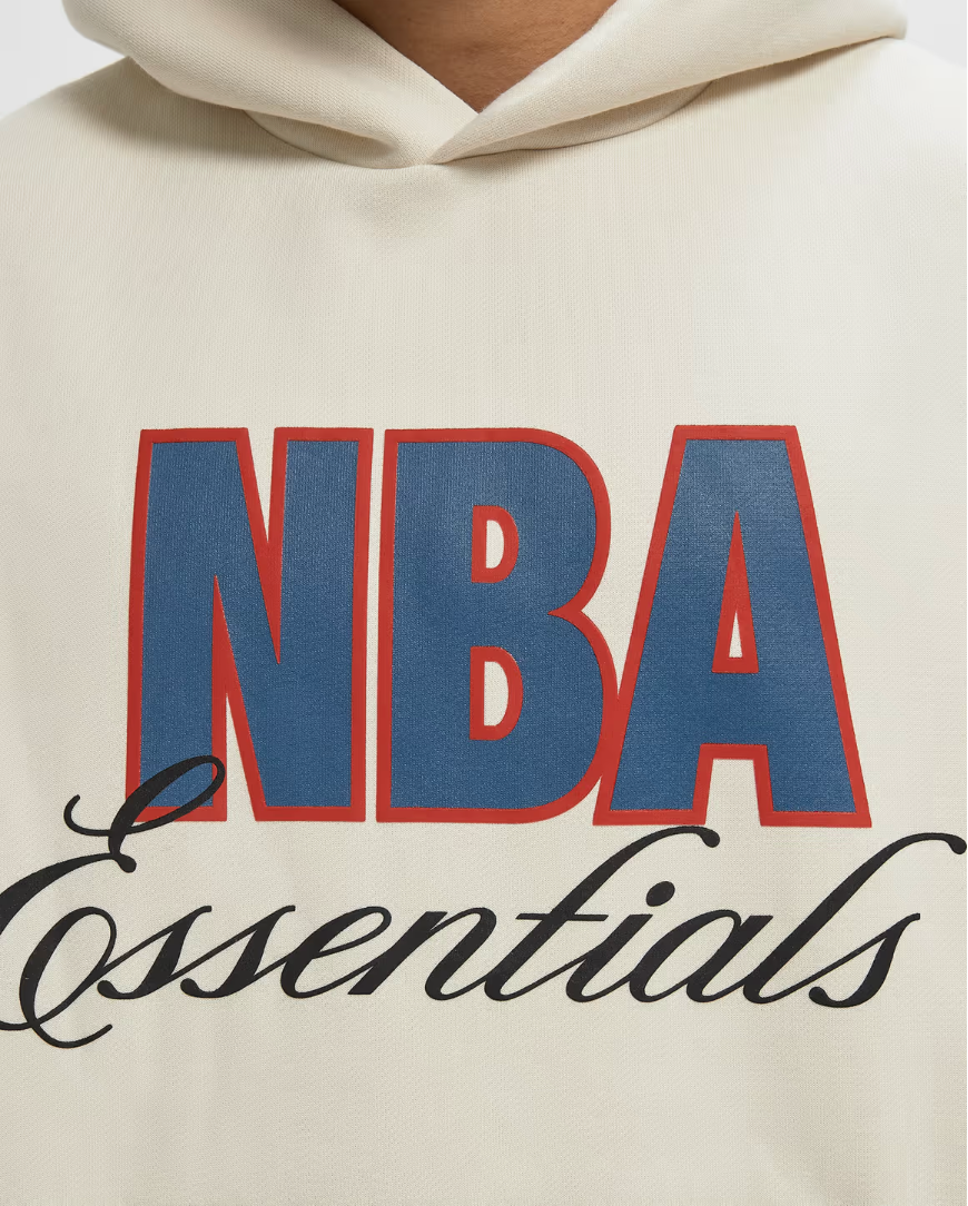 Fear of God Essentials NBA 90's Hoodie Cream White, hoodie Cream White issu de la collaboration Fear of God Essentials x NBA avec coupe ample, inspiration années 90 et finitions premium.
