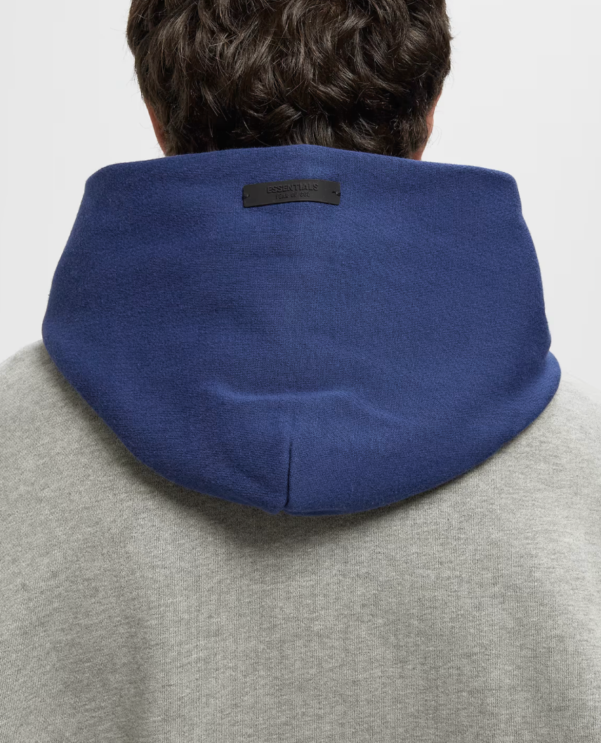 Fear of God Essentials NBA Sport Hoodie Concrete Heather/Estate Blue, hoodie gris Concrete Heather et bleu Estate Blue issu de la collaboration Fear of God Essentials x NBA avec coupe ample et finitions premium.