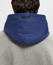 Fear of God Essentials NBA Sport Hoodie Concrete Heather/Estate Blue, hoodie gris Concrete Heather et bleu Estate Blue issu de la collaboration Fear of God Essentials x NBA avec coupe ample et finitions premium.