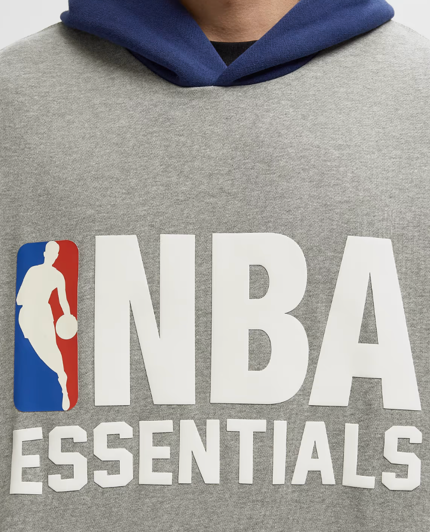 Estate Blue, hoodie gris Concrete Heather et bleu Estate Blue issu de la collaboration Fear of God Essentials x NBA avec coupe ample et finitions premium.