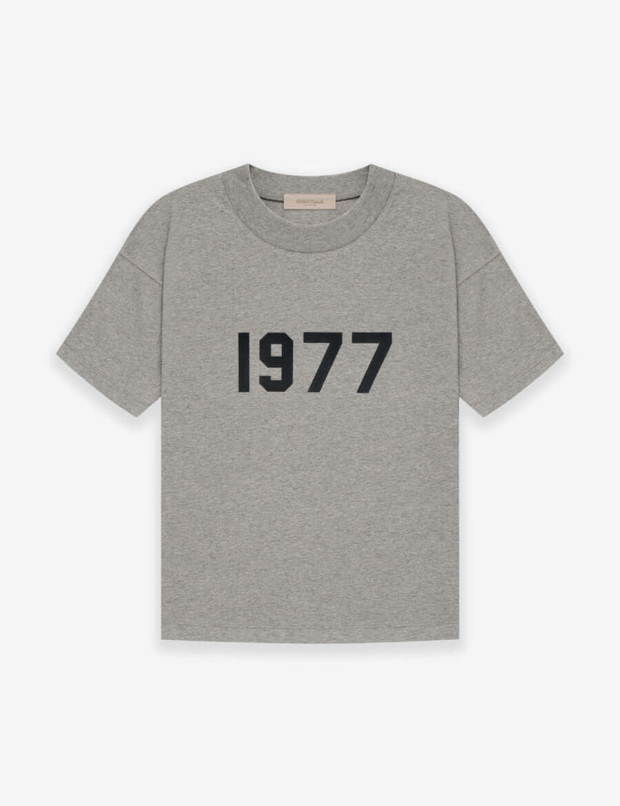 Fear of God Essentials 1977 T-Shirt Grey en tissu gris doux, avec coupe ample, manches courtes, col rond classique et marquage 1977 distinctif.