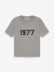 Fear of God Essentials 1977 T-Shirt Grey en tissu gris doux, avec coupe ample, manches courtes, col rond classique et marquage 1977 distinctif.