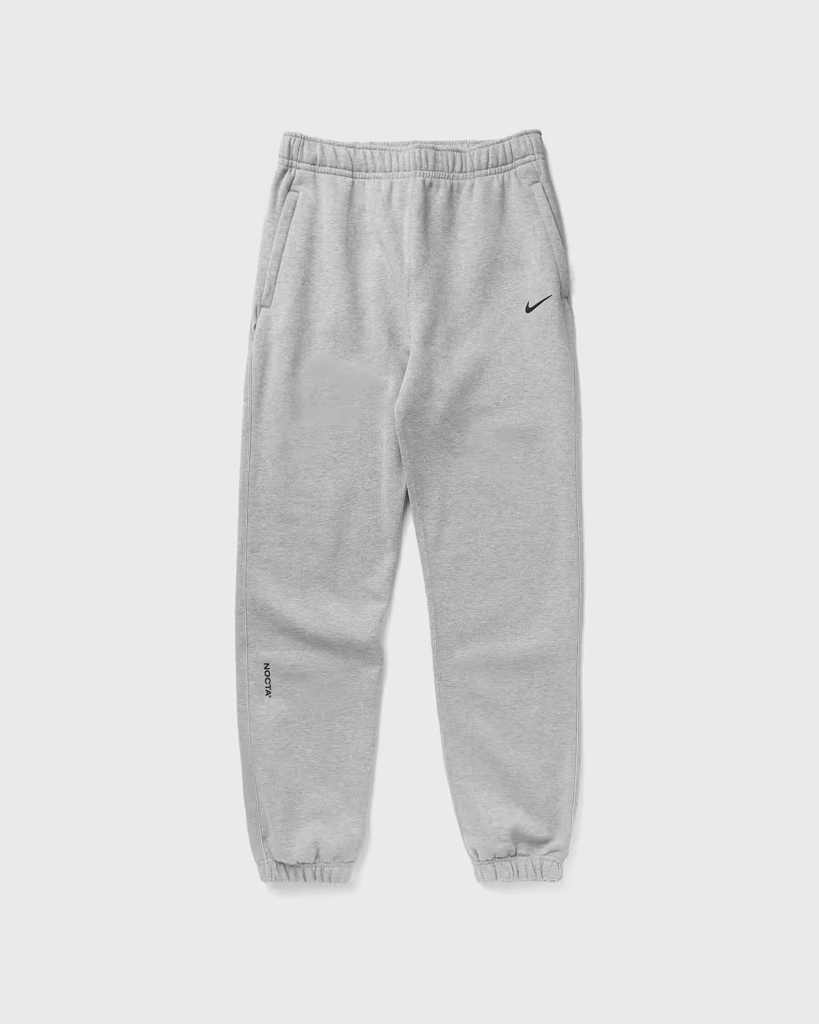 Nike x NOCTA Fleece CS Sweatpant Dark Grey Heather, pantalon fleece gris chiné avec poignets côtelés, poches zippées et détails NOCTA.