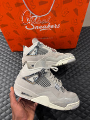 Jordan 4 Rétro Frozen Moments femme d’occasion en état 8,5/10, cuir gris perlé, détails texturés, sneaker sans boîte.