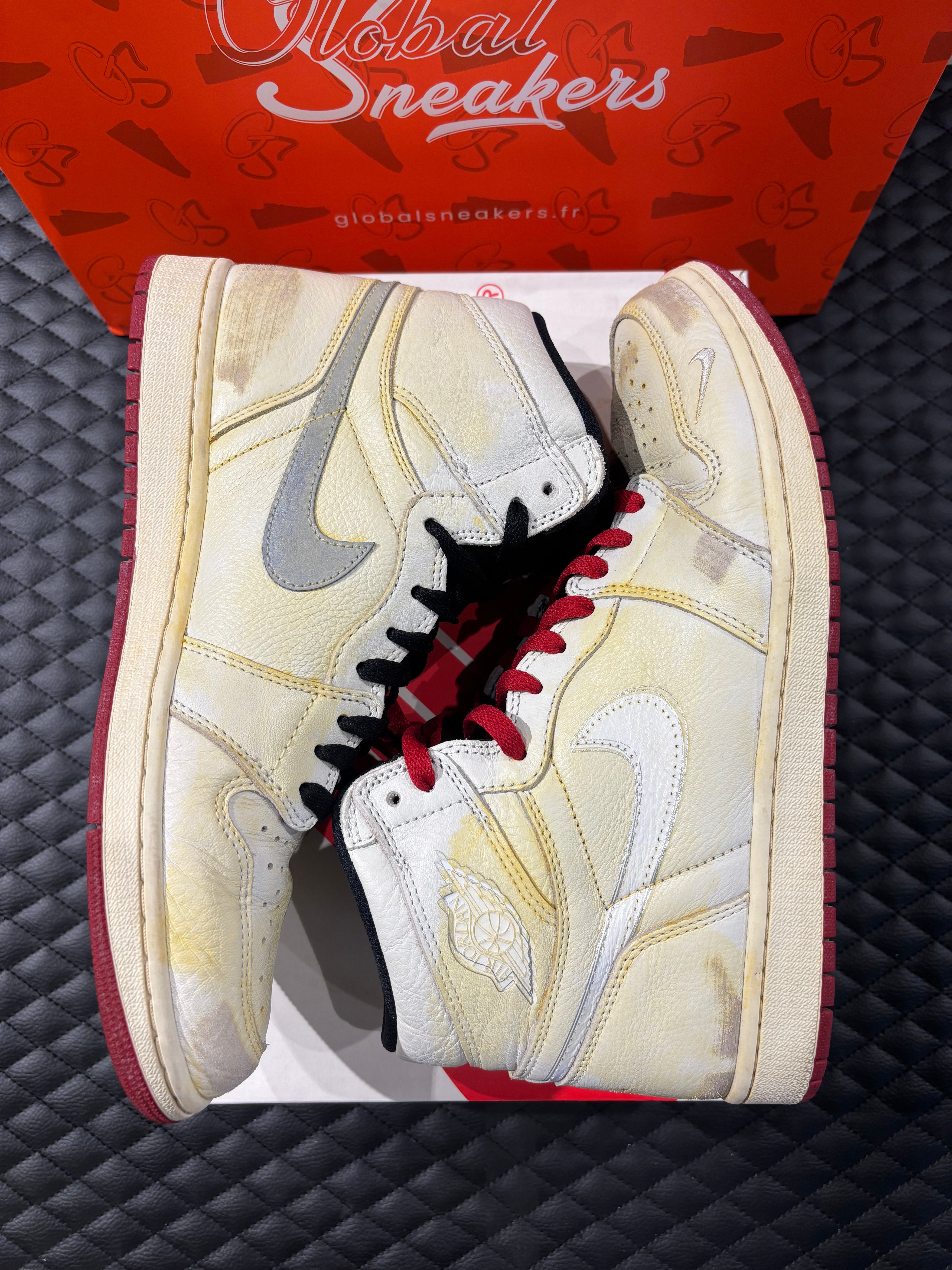 Jordan 1 High Rétro Nigel Sylvester d’occasion en état 8,5/10, cuir blanc patiné, détails crème et noirs, sneaker avec boîte.