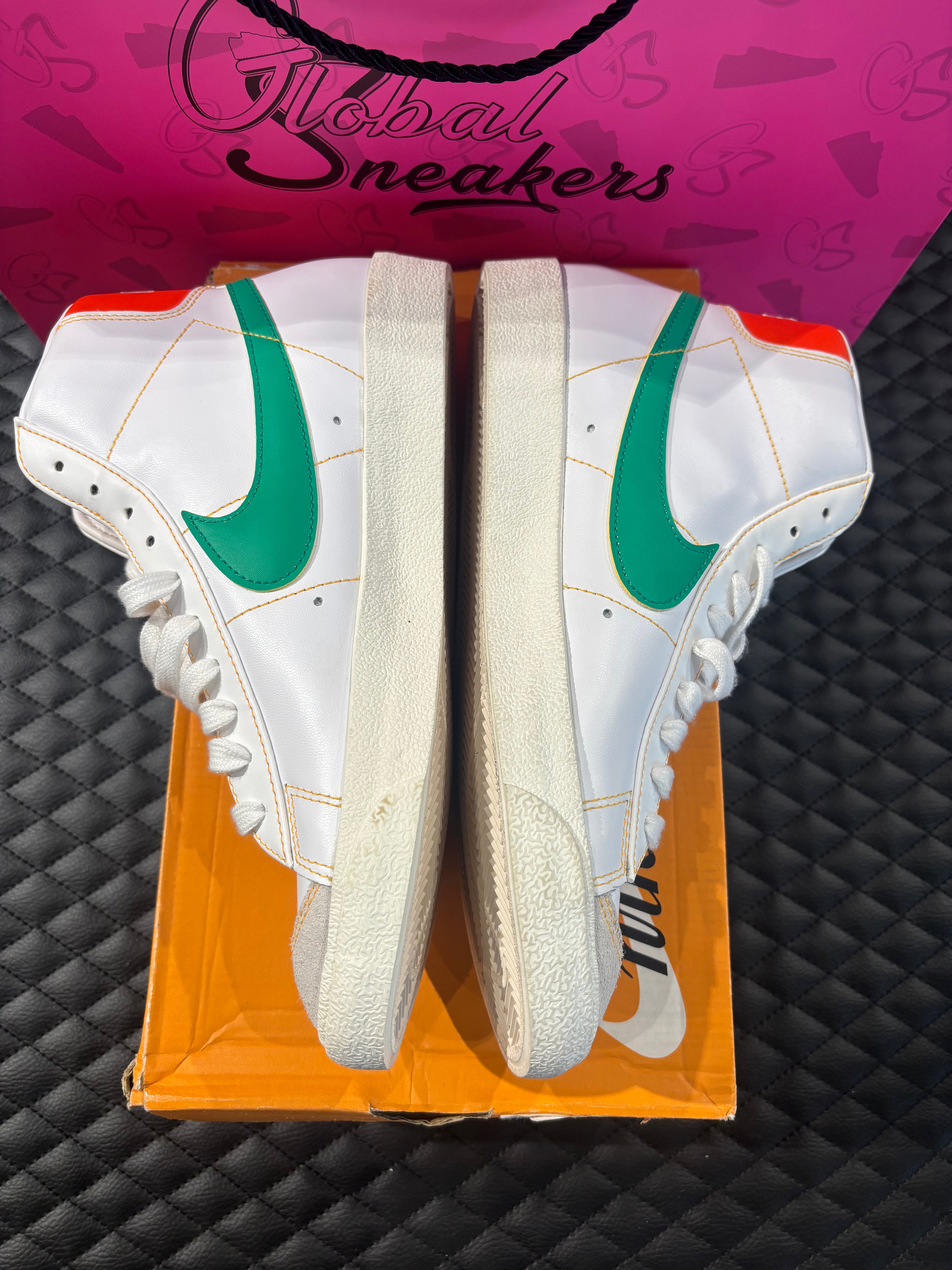 Nike Blazer Mid 77 Raygun d’occasion en état 9/10, cuir blanc, accents orange et jaune, silhouette montante classique, sneaker avec boîte.