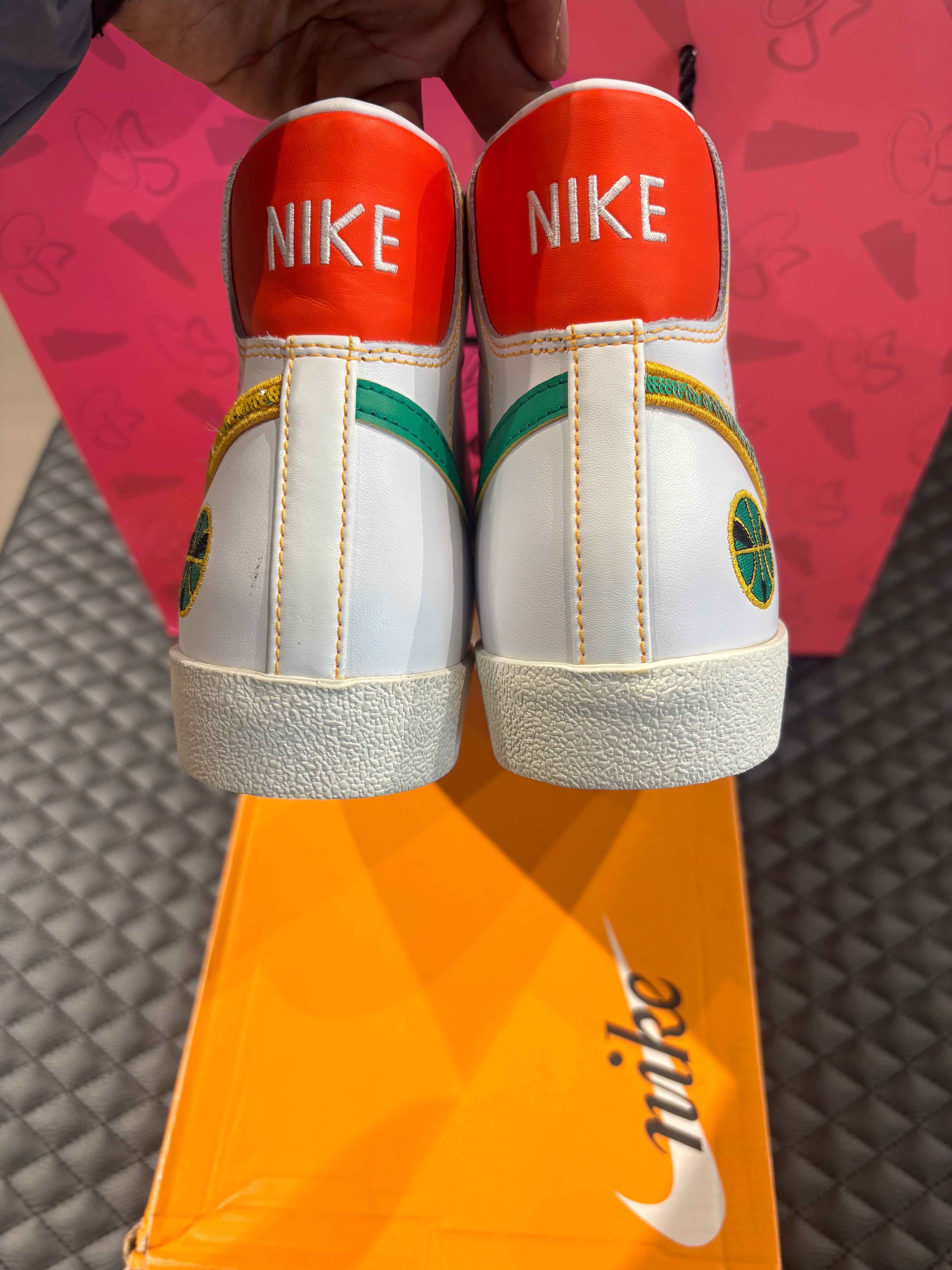 Nike Blazer Mid 77 Raygun d’occasion en état 9/10, cuir blanc, accents orange et jaune, silhouette montante classique, sneaker avec boîte.