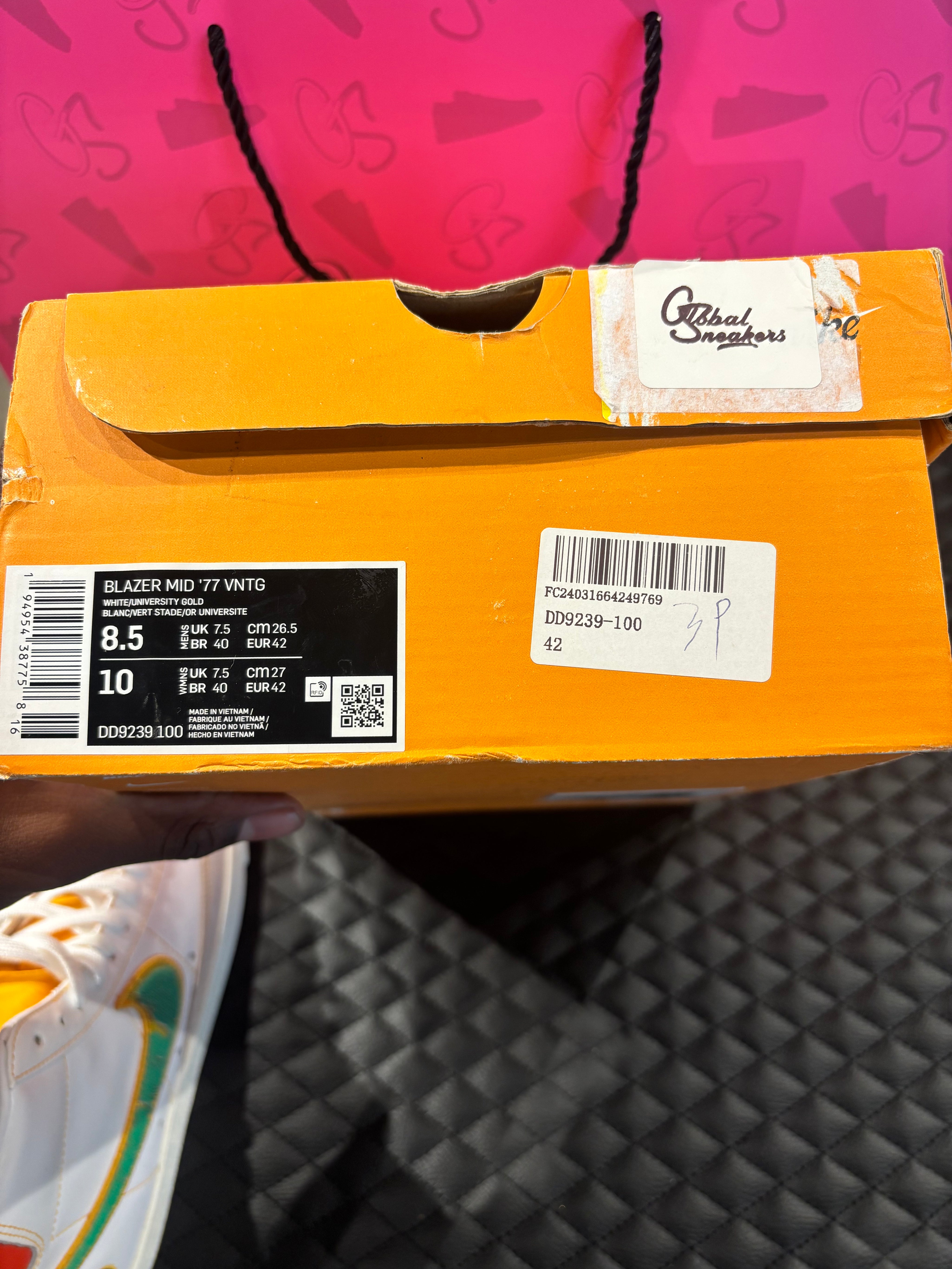 Nike Blazer Mid 77 Raygun d’occasion en état 9/10, cuir blanc, accents orange et jaune, silhouette montante classique, sneaker avec boîte.