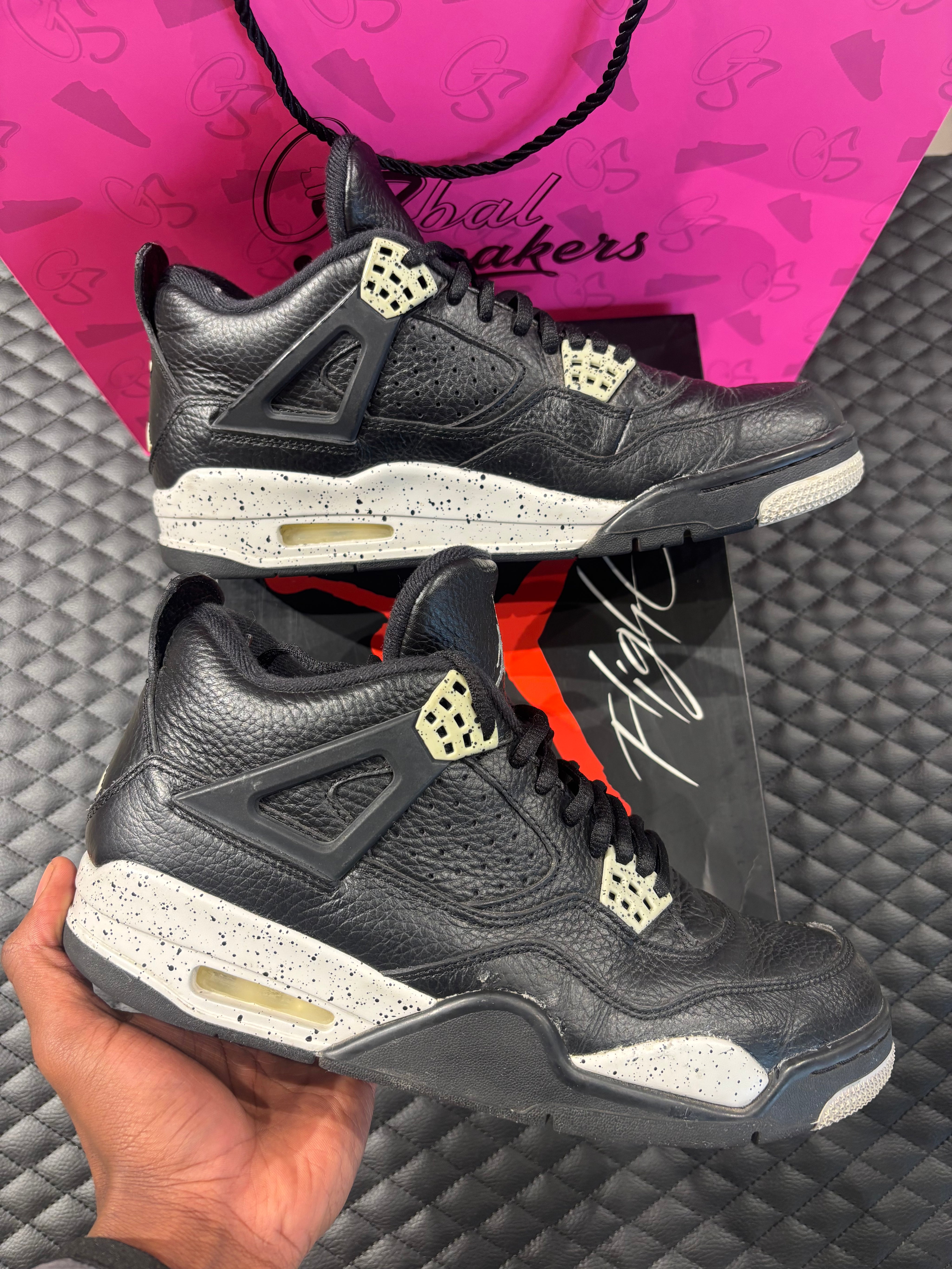 Jordan 4 Rétro Oreo d’occasion en état 8,5/10, cuir noir, détails gris mouchetés, silhouette emblématique, sneaker avec boîte.

