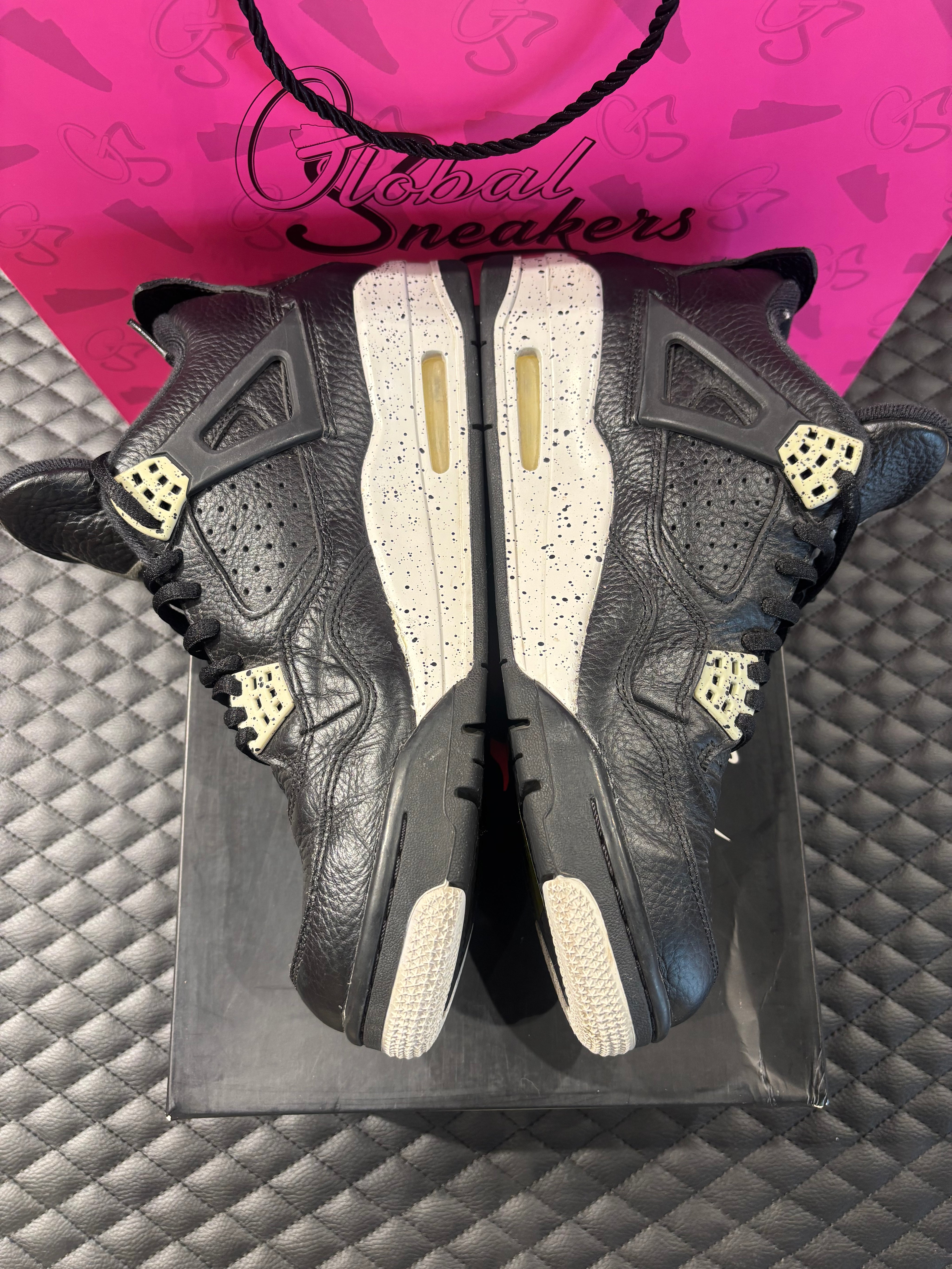 Jordan 4 Rétro Oreo d’occasion en état 8,5/10, cuir noir, détails gris mouchetés, silhouette emblématique, sneaker avec boîte.


