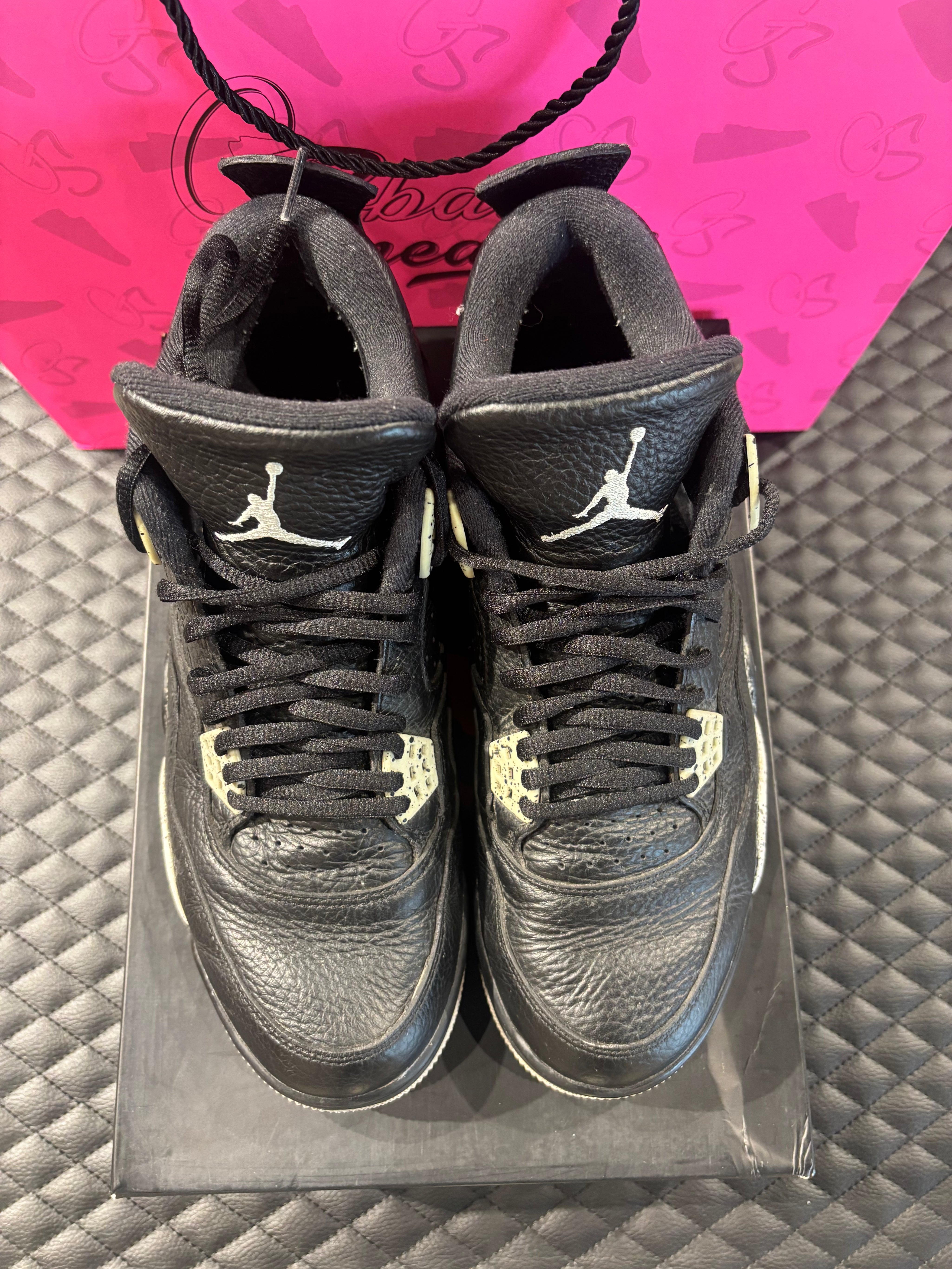 Jordan 4 Rétro Oreo d’occasion en état 8,5/10, cuir noir, détails gris mouchetés, silhouette emblématique, sneaker avec boîte.

