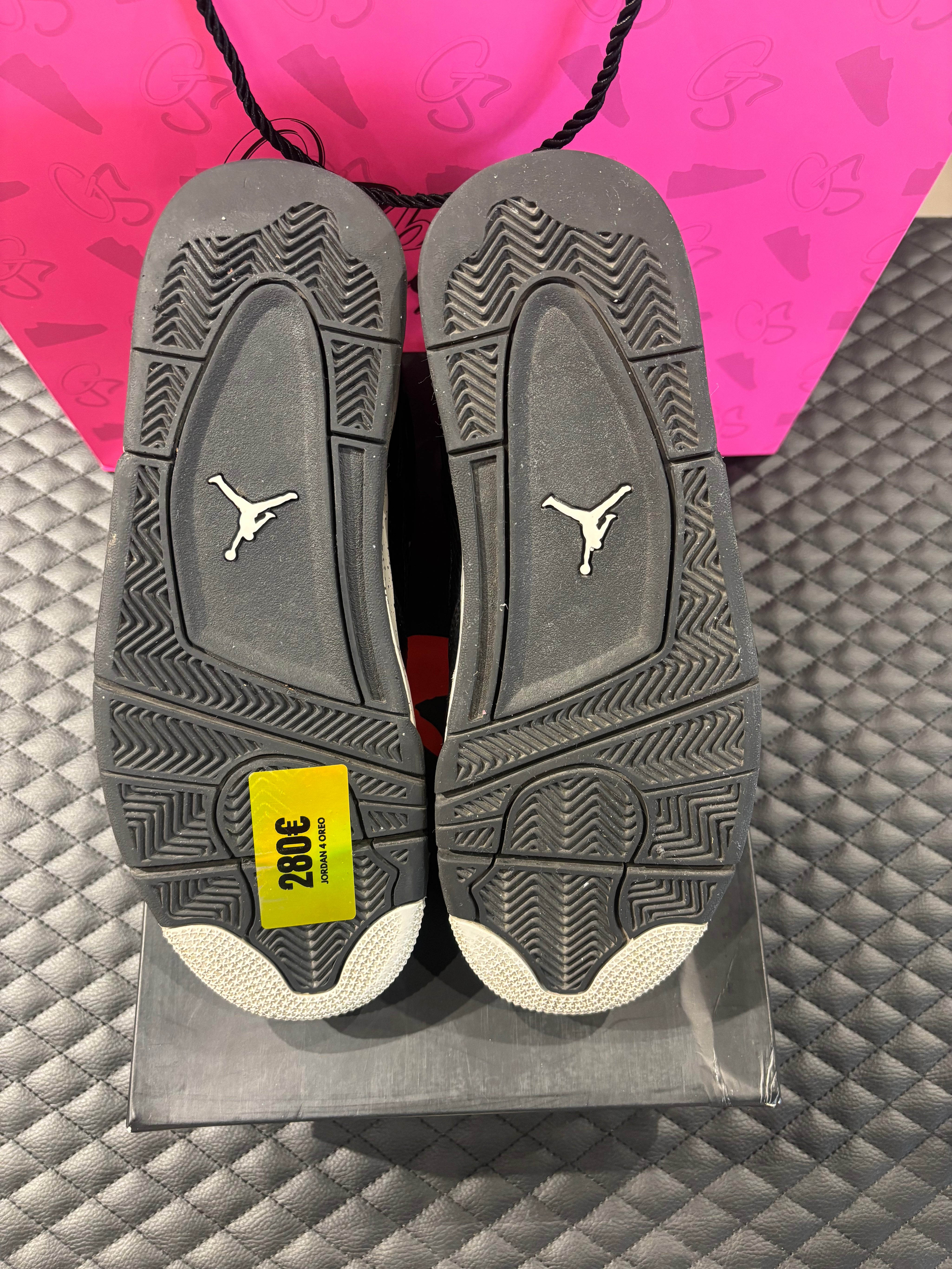 Jordan 4 Rétro Oreo d’occasion en état 8,5/10, cuir noir, détails gris mouchetés, silhouette emblématique, sneaker avec boîte.

