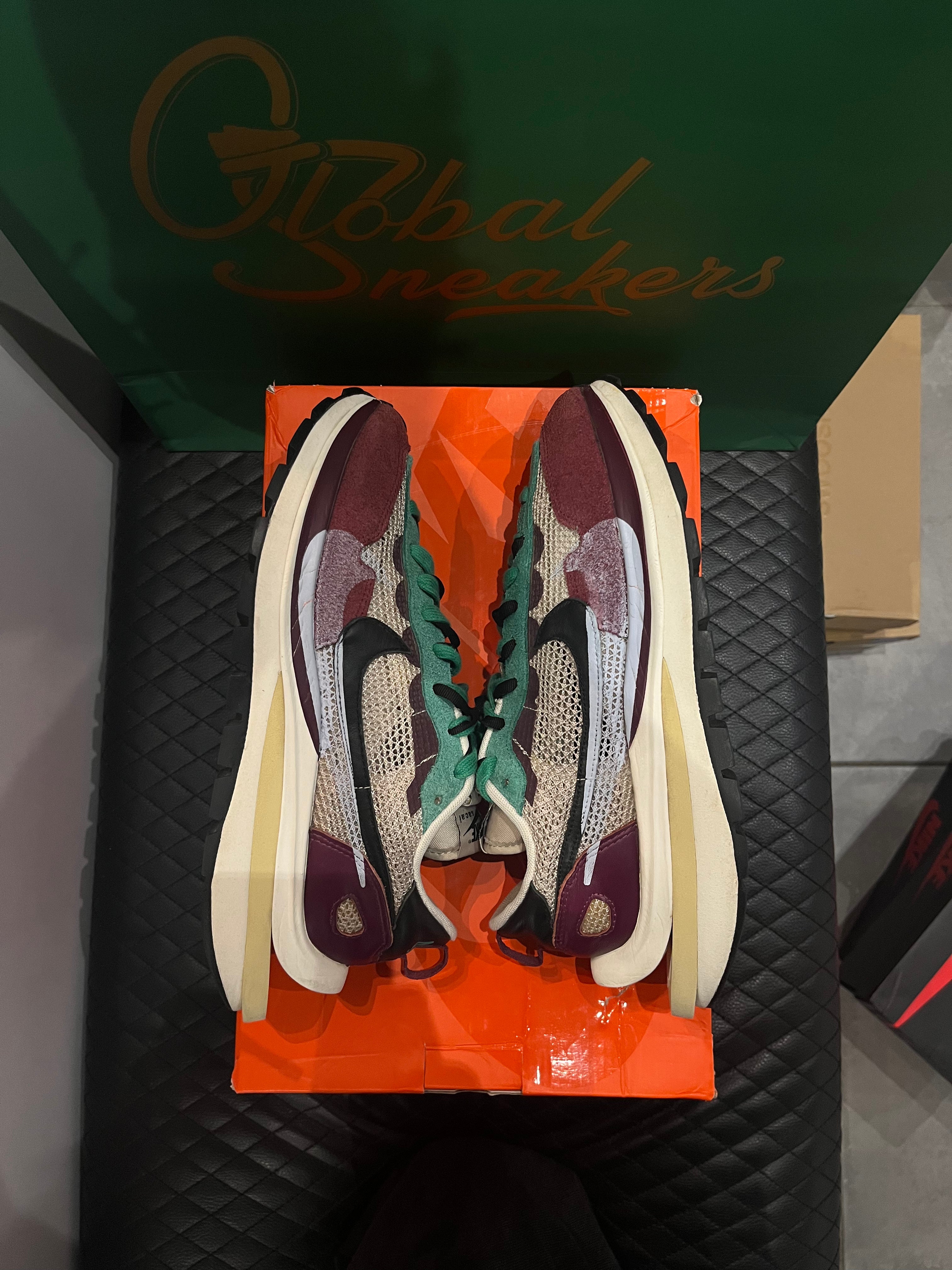 Nike Vaporwaffle Sacai Villain Red Neptune Green d’occasion en état 8,5/10, mesh, suede et cuir, coloris rouge et vert, sneaker avec boîte.
