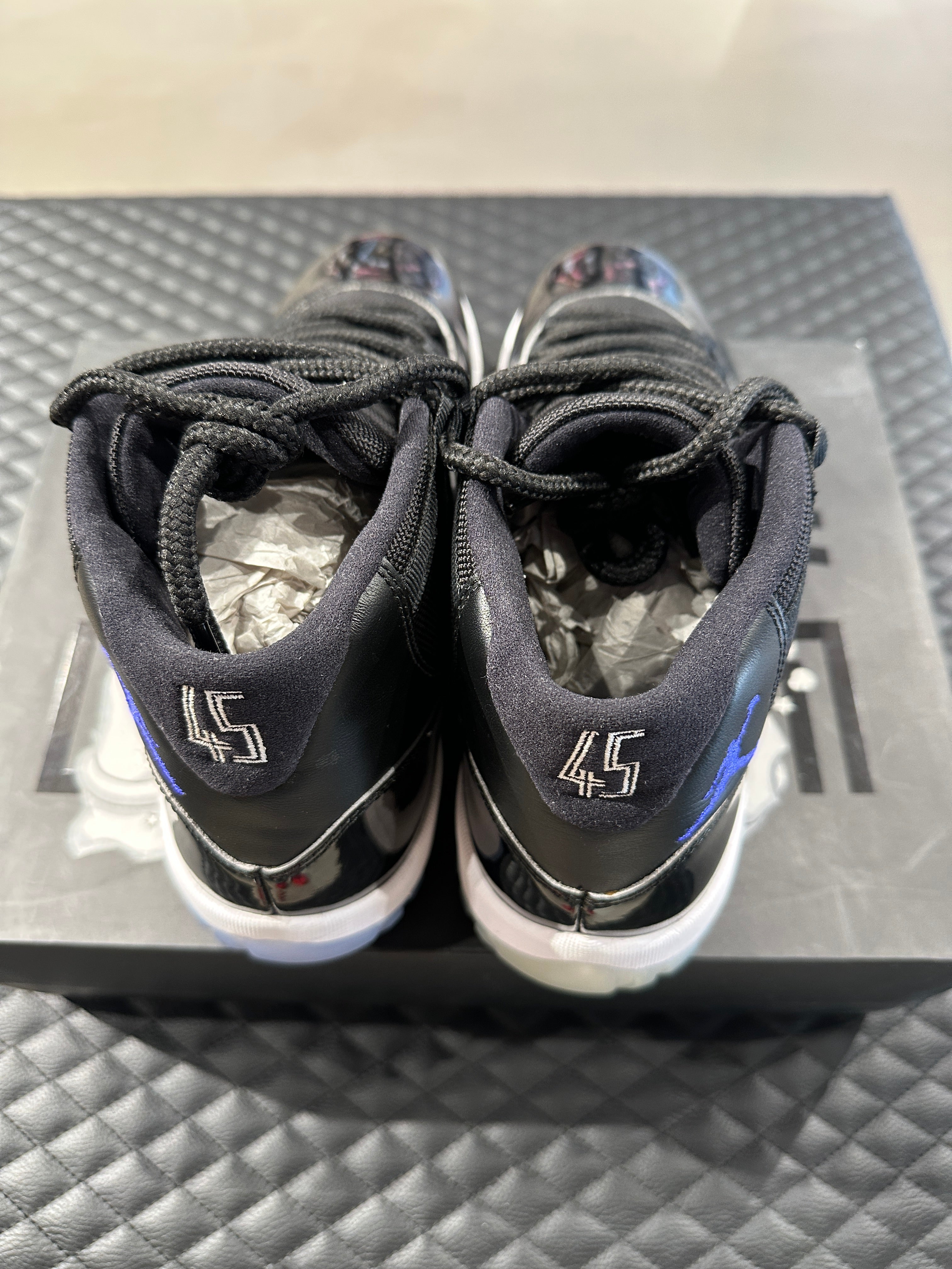 Jordan 11 Retro Space Jam 2016 d’occasion, cuir verni noir, mesh balistique, semelle translucide, sneaker en bon état général. 