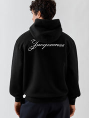 Jacquemus Le Hoodie Logo Brodé en coton molletonné avec coupe ample, petit logo J brodé sur la poitrine et signature Jacquemus au dos.