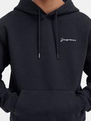 Jacquemus Le Sweatshirt Brodé Embroidered Logo Regular Fit Hoodie Black/White, hoodie Jacquemus noir à coupe Regular Fit avec logo blanc brodé et capuche.
