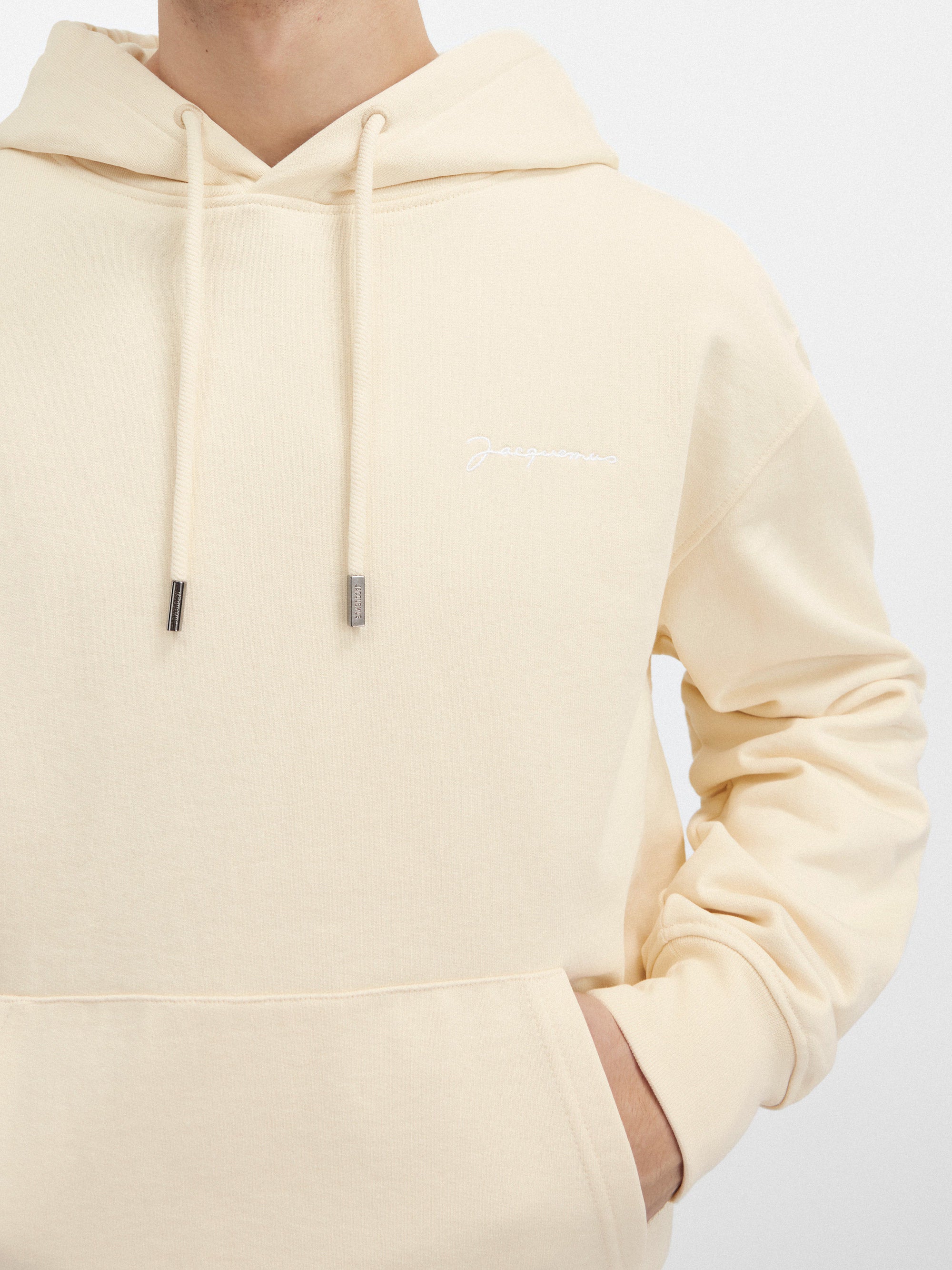 Jacquemus Le Sweatshirt Brodé Embroidered Logo Regular Fit Hoodie Dark Beige, hoodie Jacquemus beige foncé à coupe Regular Fit avec logo brodé et capuche.