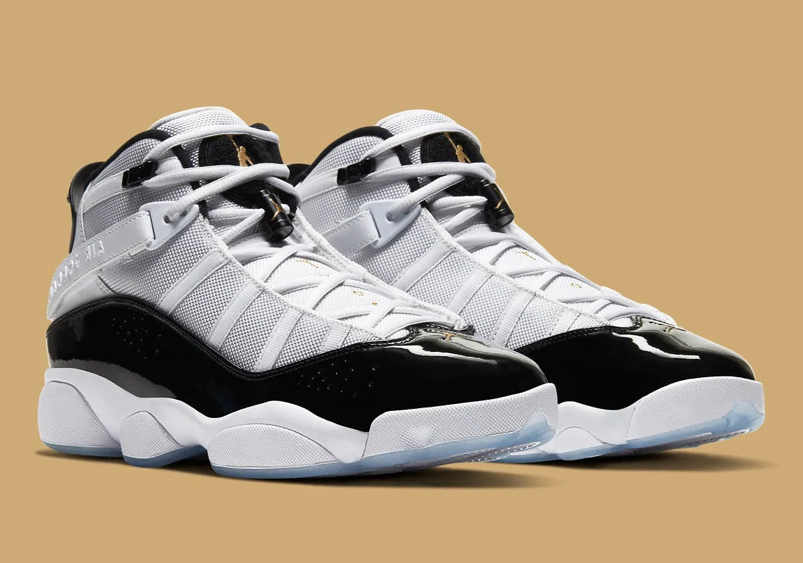 Air Jordan 6 Rings Defining Moments en blanc et noir avec empiècements en cuir verni, détails Metallic Gold et semelle translucide.