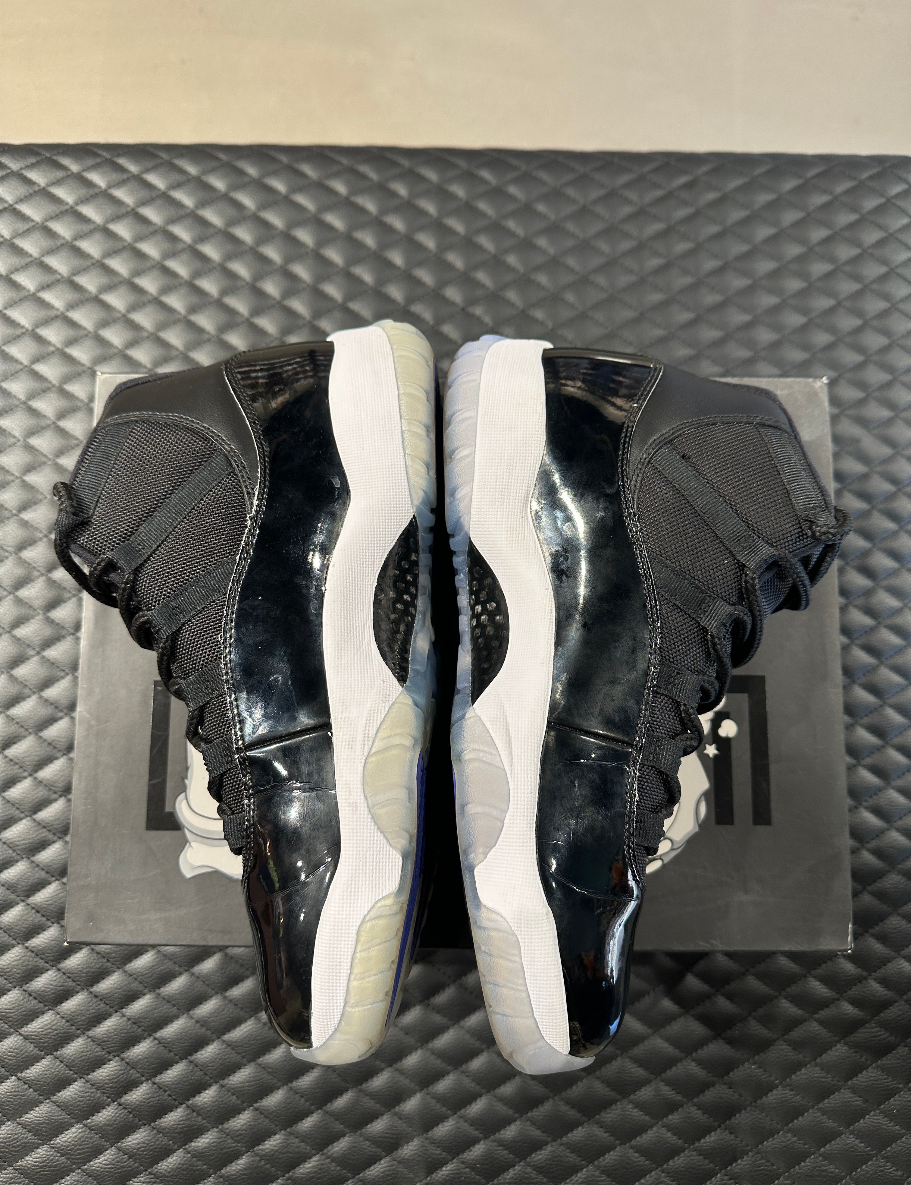 Jordan 11 Retro Space Jam 2016 d’occasion, cuir verni noir, mesh balistique, semelle translucide, sneaker en bon état général.