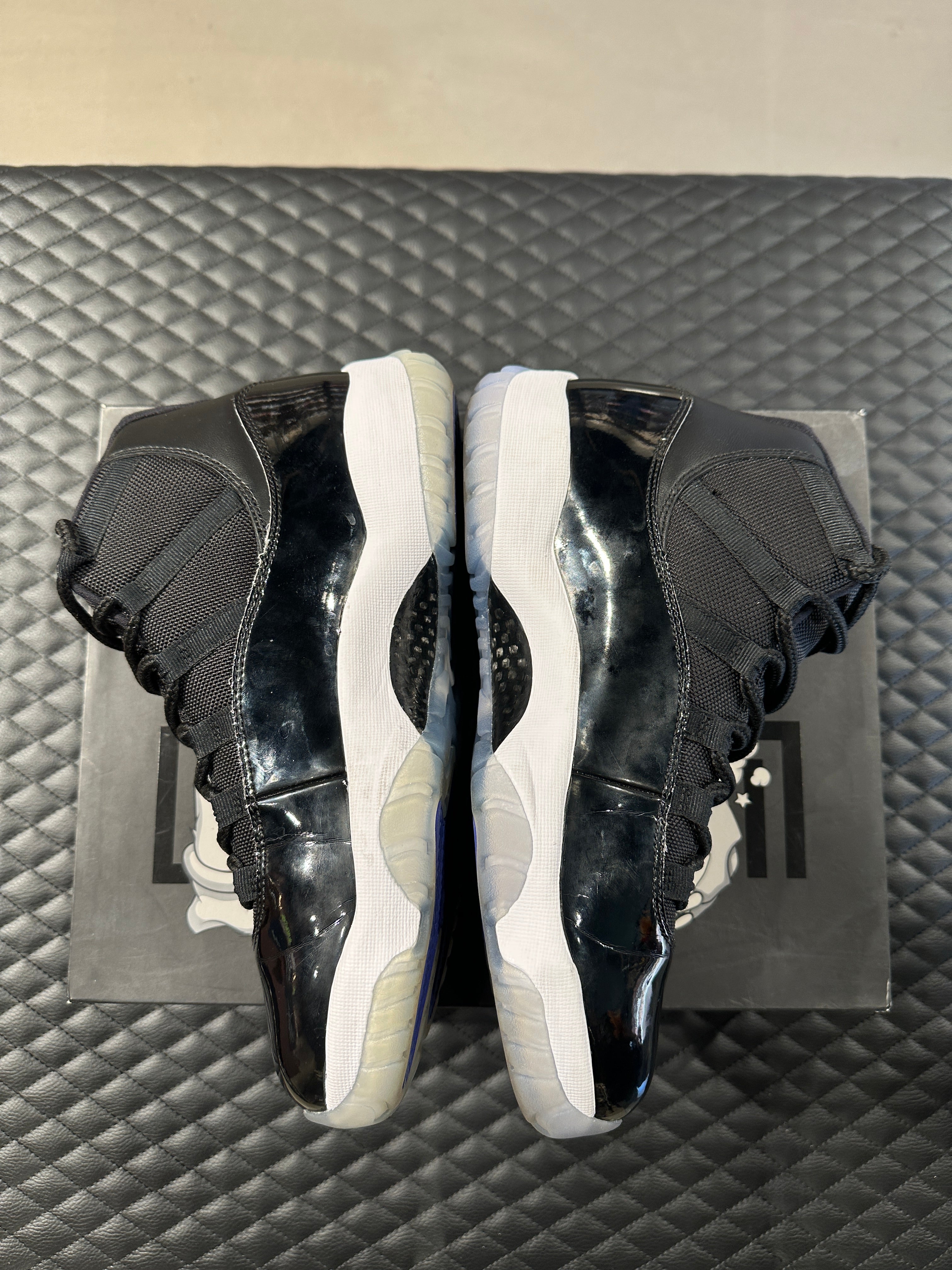 Jordan 11 Retro Space Jam 2016 d’occasion, cuir verni noir, mesh balistique, semelle translucide, sneaker en bon état général.