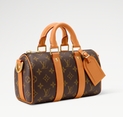 Louis Vuitton Keepall Bandoulière 25 Monogram en toile Monogram avec garnitures en cuir naturel, poignées roulées, bandoulière réglable et amovible, fermeture zippée à double curseur et finitions métalliques.